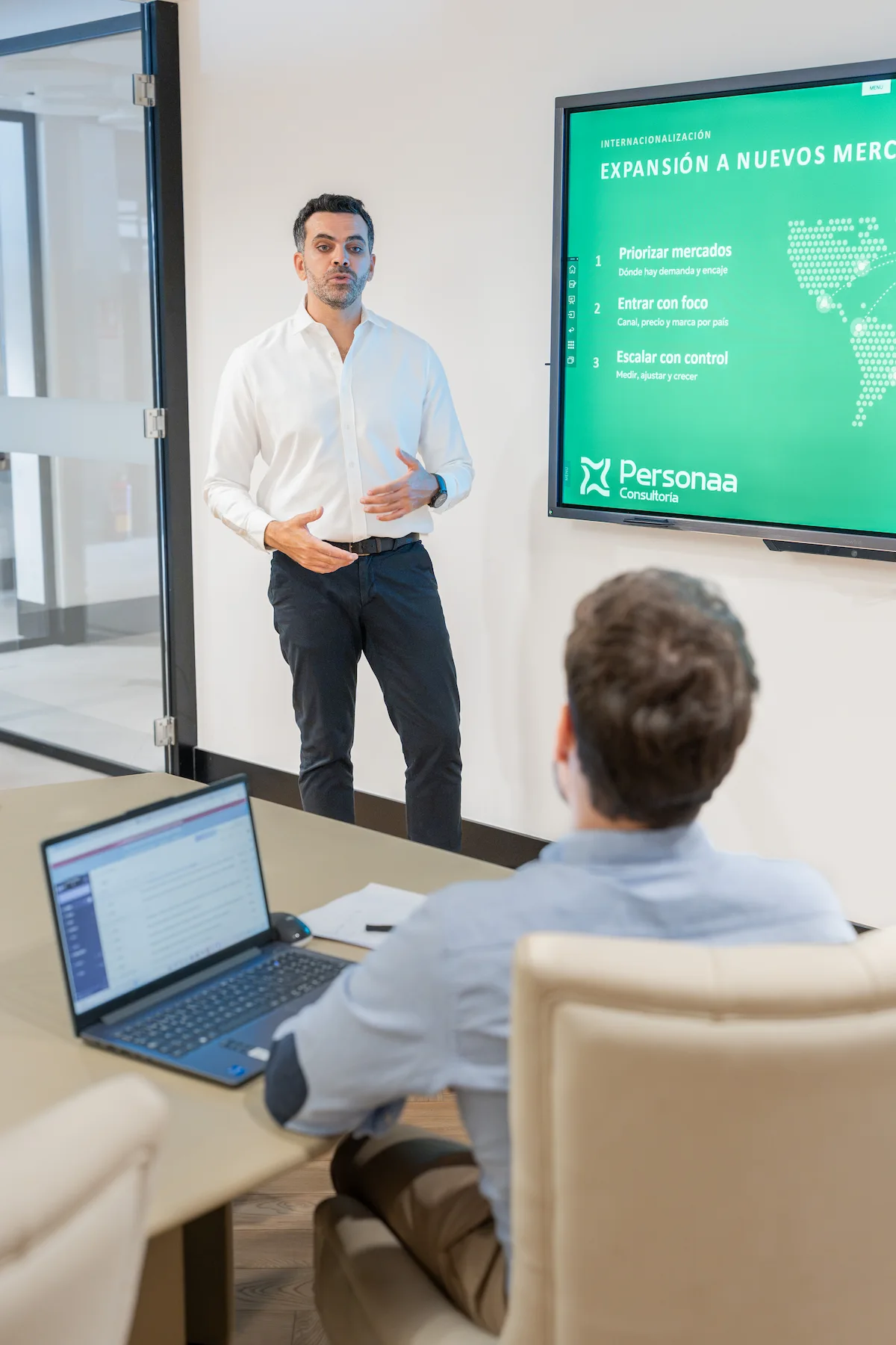 Consultant presenting an international expansion plan on a large screen during a team meeting